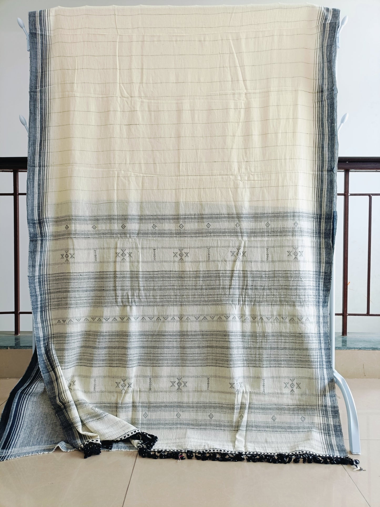 Beige and black striped fabric draped over a chair with a neutral background