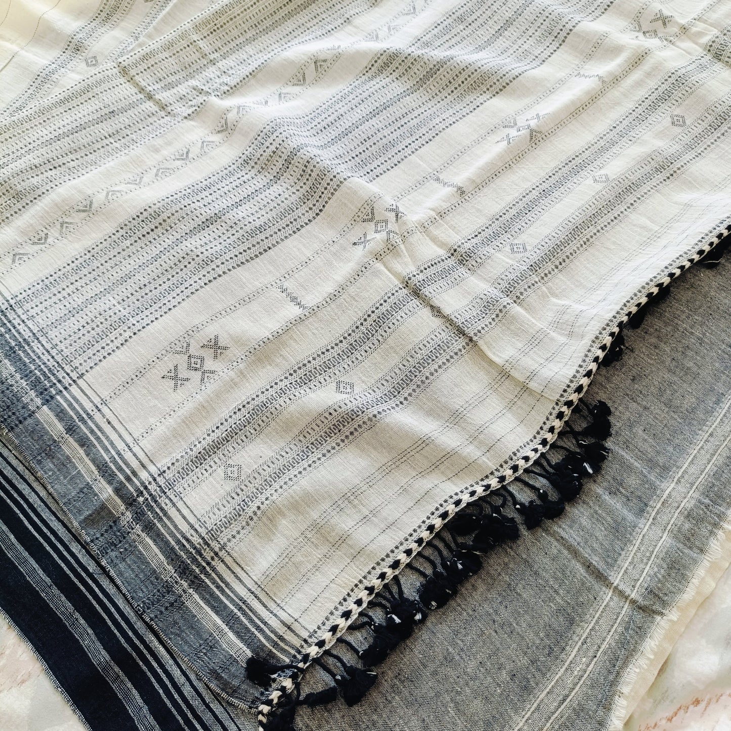 Textile with intricate patterns and tassels on a neutral background