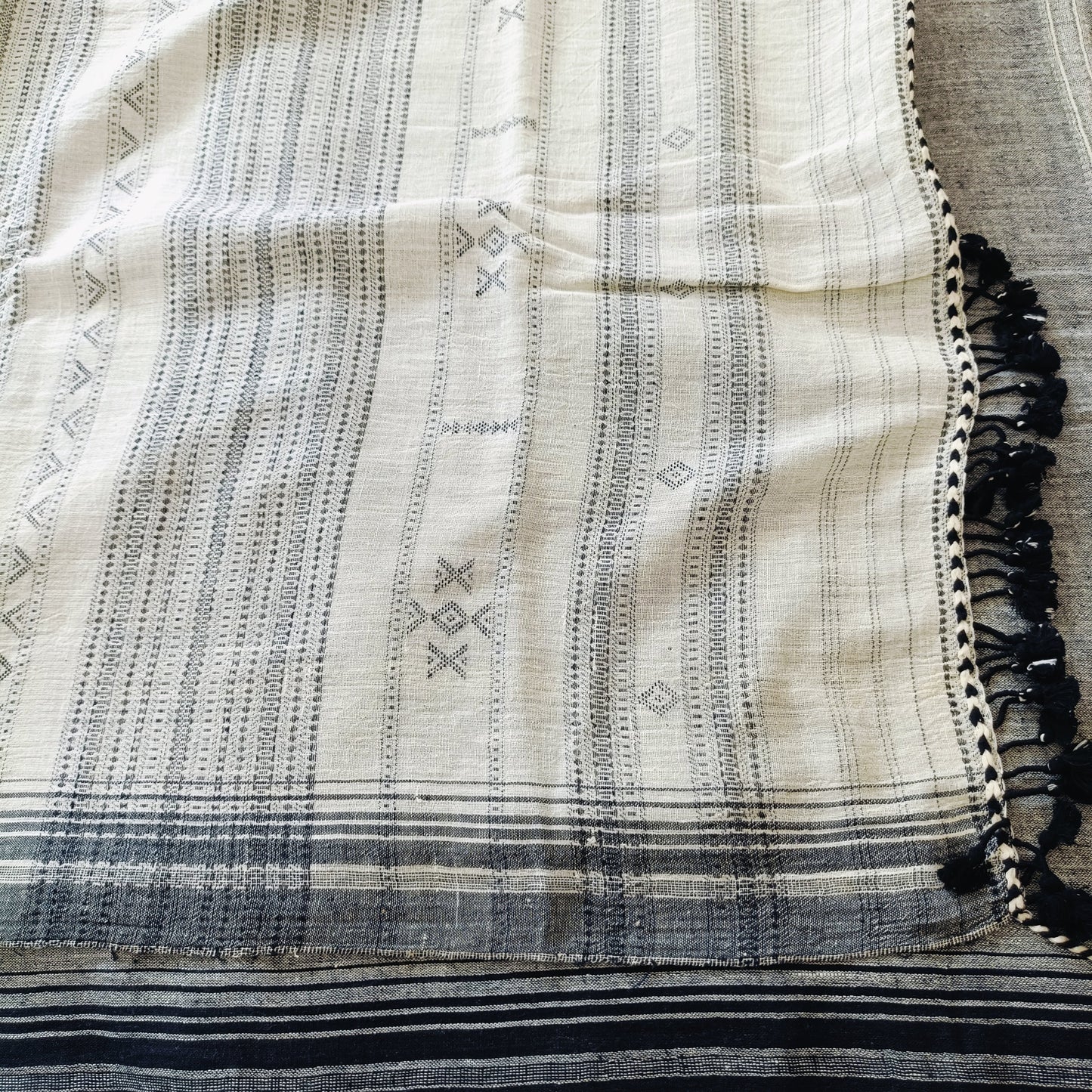 Textile with black and white patterns and tassels on a neutral background