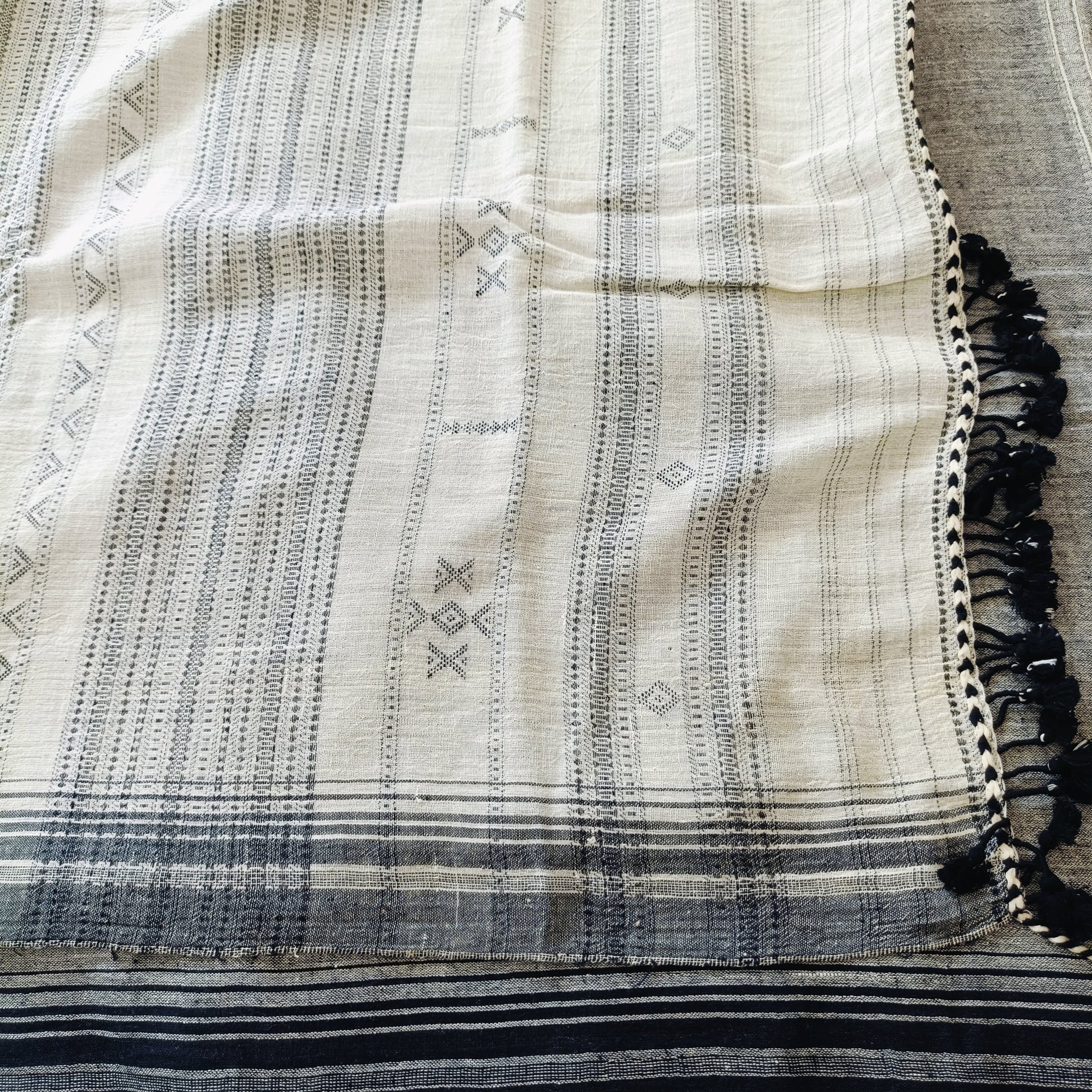 Textile with black and white patterns and tassels on a neutral background