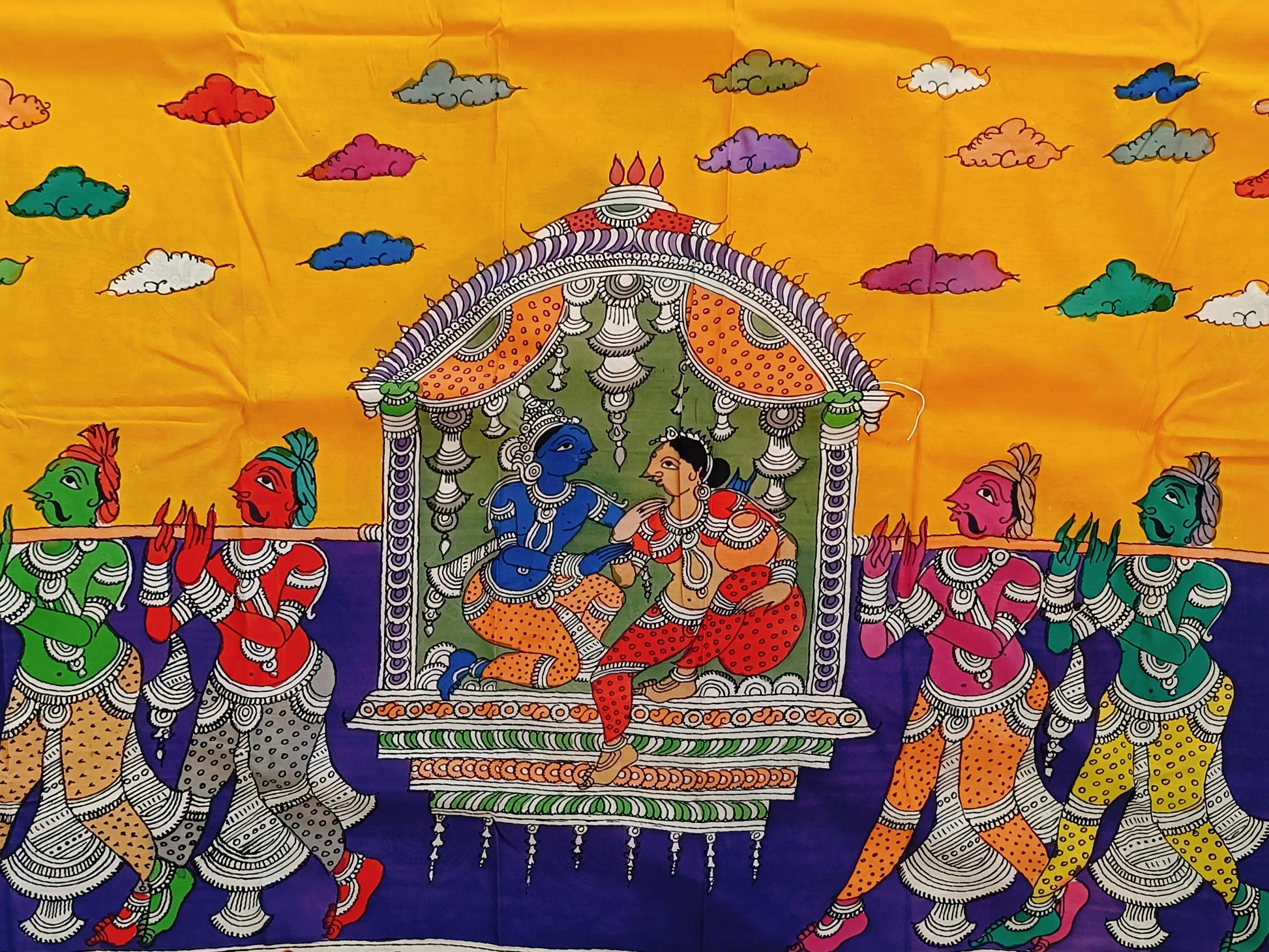 Colorful traditional fabric with a scene of people and architecture on a yellow and blue background.