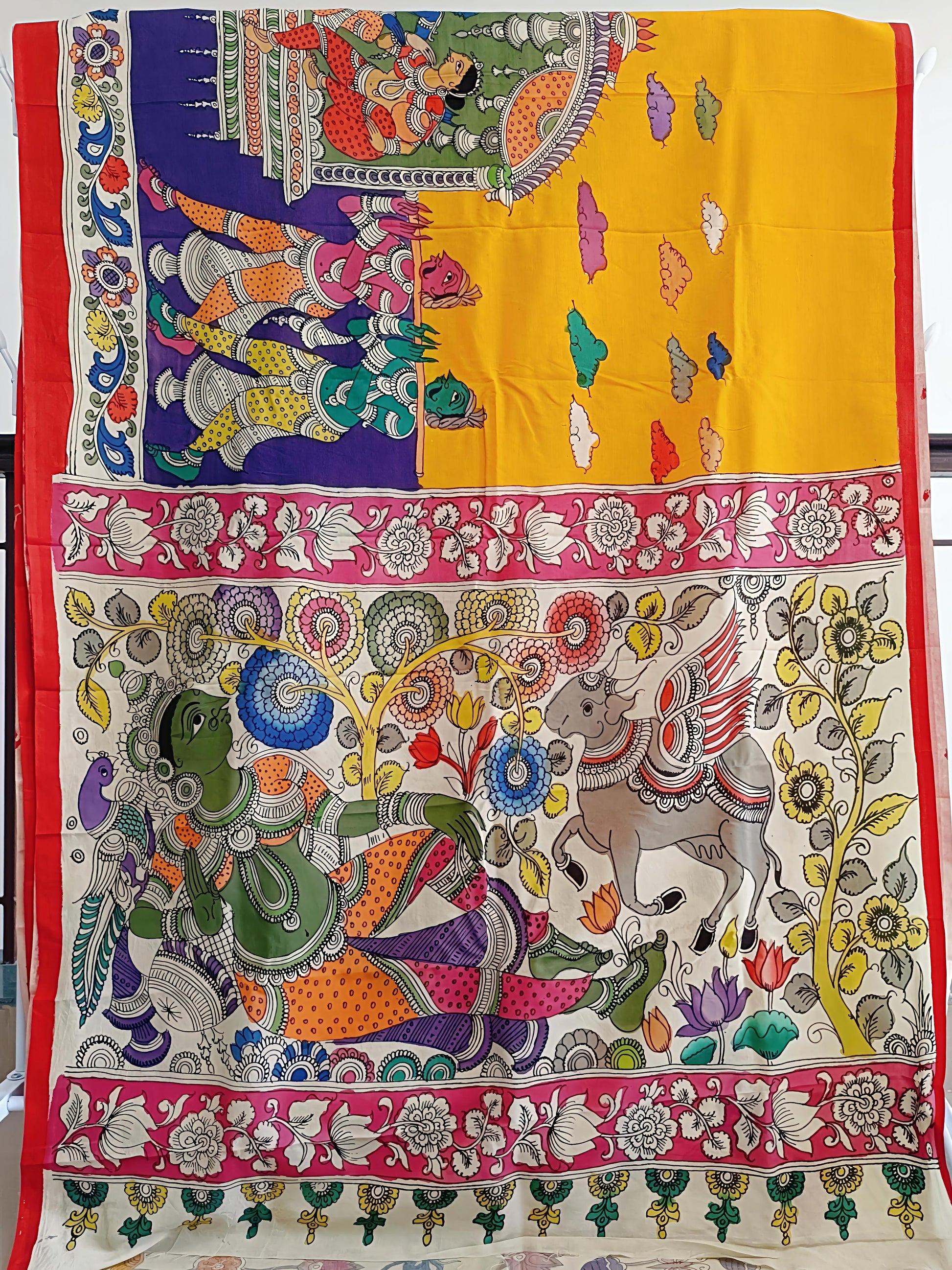 Colorful fabric with intricate designs of elephants and other elements on a yellow background